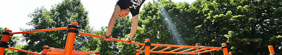 Sportler/innen üben an einer Calisthenics-Anlage in einem Wiener Park