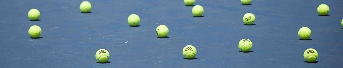 Tennisbälle liegen ungeordnet am Tennisplatz